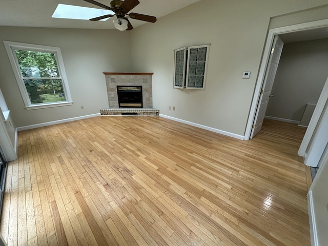 53 Pennacook Cir, Wells, ME 04090 - unfurnished living room with a ceiling fan, light wood-style flooring, a skylight, and a brick fireplace