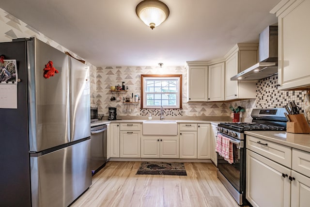 51 Burwell Ave, South Portland, ME 04106 - kitchen featuring stainless steel appliances, wall chimney exhaust hood, light countertops, backsplash, and light wood-style floors
