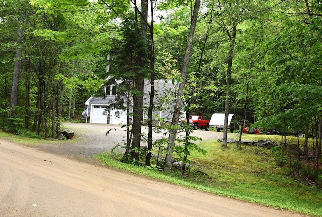 107 Shady Ln, Newport, ME 04953 - view of property hidden behind natural elements with driveway, a garage, and a view of trees