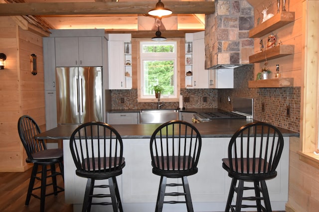 107 Shady Ln, Newport, ME 04953 - kitchen featuring stainless steel fridge, open shelves, dark countertops, beam ceiling, and wood walls