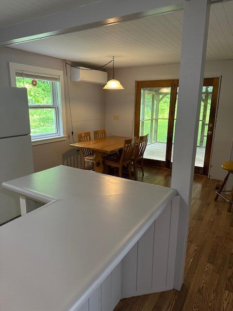 2073 Western Ave, Newburgh, ME 04444 - kitchen featuring freestanding refrigerator, a wall unit AC, dark wood finished floors, healthy amount of natural light, and beamed ceiling