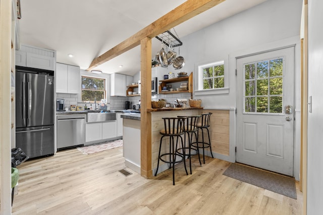 665 Hendricks Hill Rd, Southport, ME 04576 - kitchen with appliances with stainless steel finishes, decorative backsplash, beam ceiling, light wood finished floors, and white cabinets