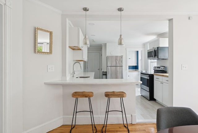 32 State St Unit 5, Portland, ME 04101 - kitchen with appliances with stainless steel finishes, a peninsula, a breakfast bar area, light wood finished floors, and ornamental molding