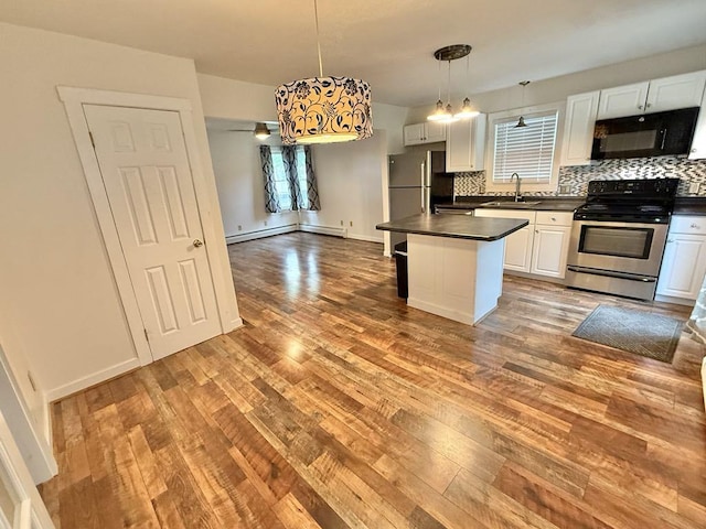 10 Turgeon St, Lewiston, ME 04240 - kitchen with stainless steel appliances, dark countertops, baseboard heating, and hardwood / wood-style flooring