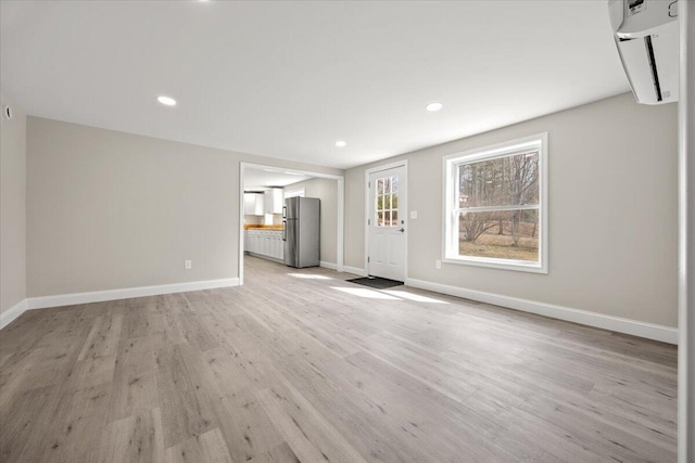 184 Jackson Rd, Waldoboro, ME 04572 - unfurnished living room featuring an AC wall unit, light wood finished floors, and recessed lighting