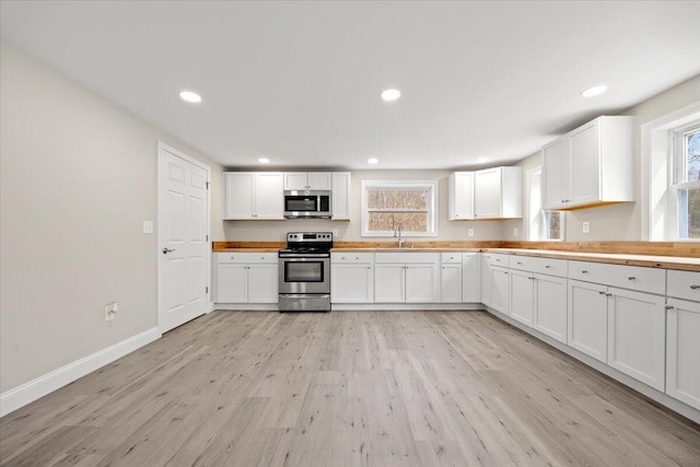 184 Jackson Rd, Waldoboro, ME 04572 - kitchen featuring appliances with stainless steel finishes, light wood finished floors, healthy amount of natural light, recessed lighting, and white cabinetry