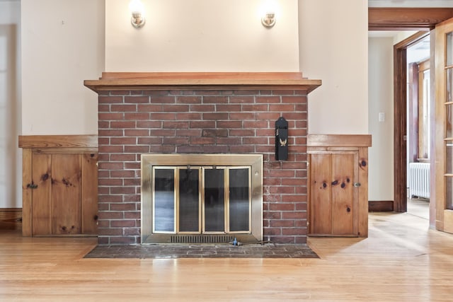 198 N St, Bath, ME 04530 - detailed view of radiator heating unit, a brick fireplace, and wood finished floors