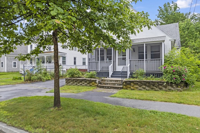 198 N St, Bath, ME 04530 - view of front facade featuring roof with shingles, a front lawn, and a sunroom