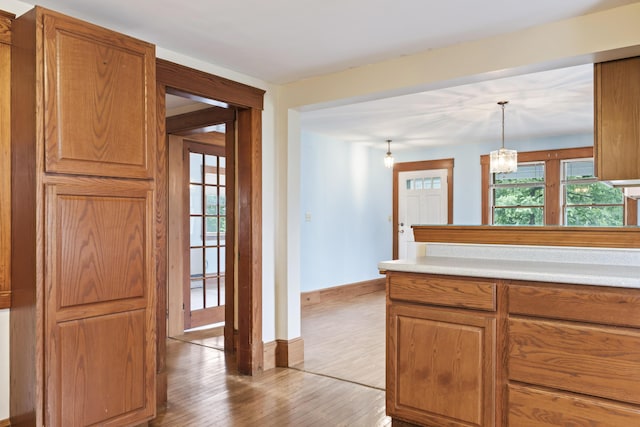 198 N St, Bath, ME 04530 - kitchen featuring light wood finished floors, brown cabinets, light countertops, and decorative light fixtures