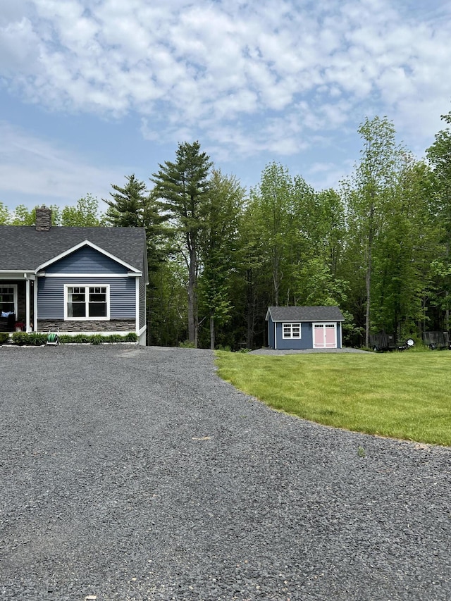 72 Cedar St, Calais, ME 04619 - view of side of property featuring stone siding, a lawn, a chimney, an outdoor structure, and gravel driveway