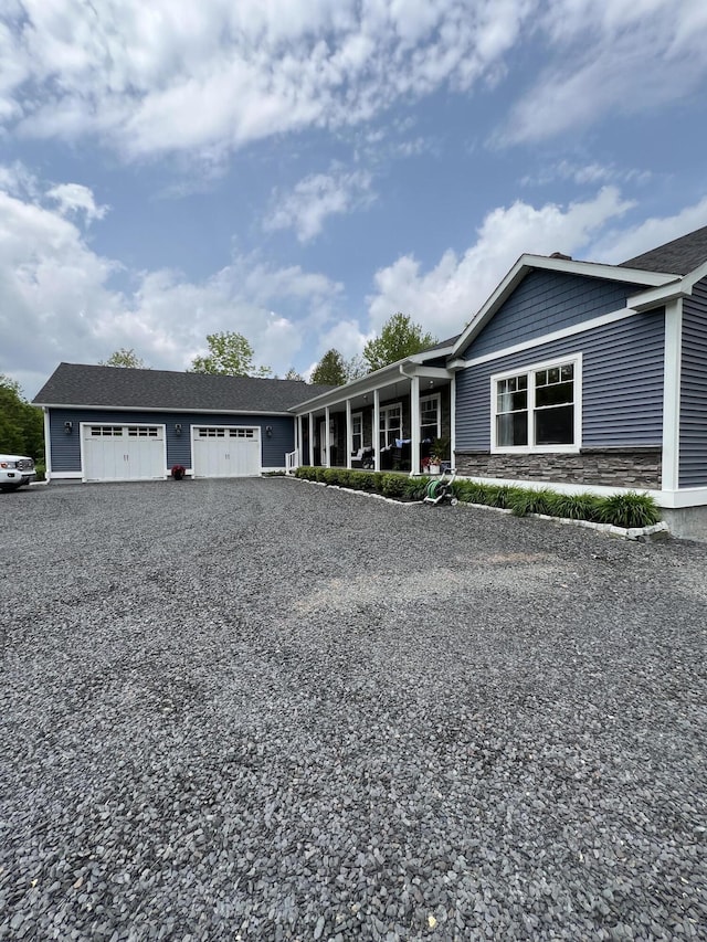 72 Cedar St, Calais, ME 04619 - ranch-style house with an attached garage, gravel driveway, stone siding, and a porch