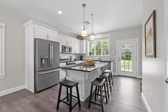 30 Pepperell Way Unit 58, Arundel, ME 04046 - kitchen featuring appliances with stainless steel finishes, white cabinets, a kitchen bar, dark wood-style floors, and a kitchen island