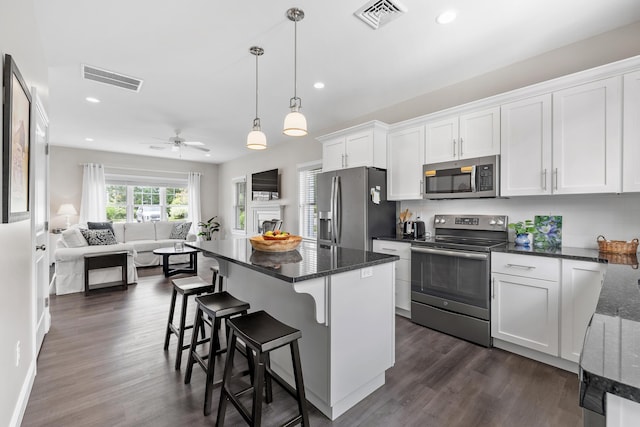 30 Pepperell Way Unit 58, Arundel, ME 04046 - kitchen featuring stainless steel appliances, open floor plan, white cabinetry, a breakfast bar area, and dark wood-style flooring