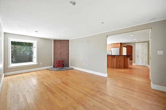 18 Fern Ave, Falmouth, ME 04105 - unfurnished living room featuring arched walkways, light wood-style floors, a wood stove, recessed lighting, and crown molding