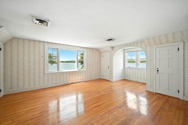 18 Fern Ave, Falmouth, ME 04105 - unfurnished living room featuring wallpapered walls, wood finished floors, arched walkways, and a water view