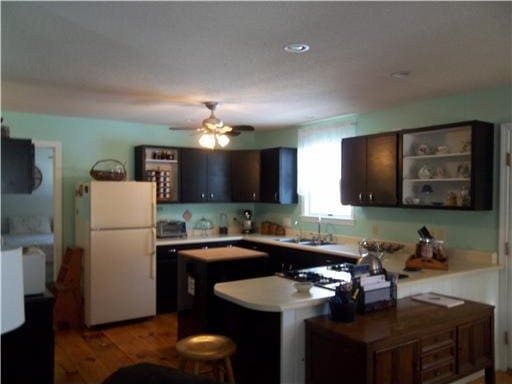 1 Weather Way, Dover-Foxcroft, ME 04426 - kitchen with freestanding refrigerator, ceiling fan, a peninsula, dark brown cabinets, and open shelves