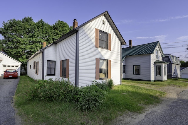 7 Hazen St, Norway, ME 04268 - view of front of house with a chimney, driveway, a detached garage, and an outbuilding