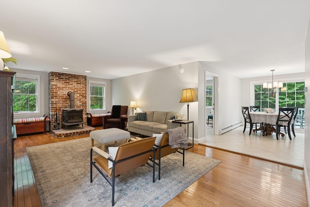 3 Flintlock Ln, Falmouth, ME 04105 - living area featuring a wood stove, a baseboard radiator, light wood finished floors, and a chandelier