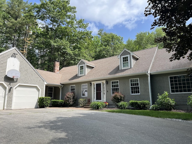 3 Flintlock Ln, Falmouth, ME 04105 - cape cod house with roof with shingles, a garage, asphalt driveway, a chimney, and view of wooded area