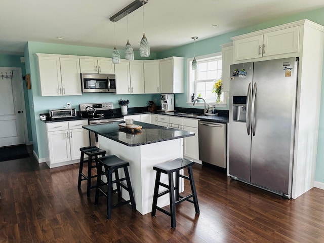 905 Blackstream Rd, Hermon, ME 04401 - kitchen with stainless steel appliances, white cabinetry, a kitchen breakfast bar, dark wood-type flooring, and decorative light fixtures