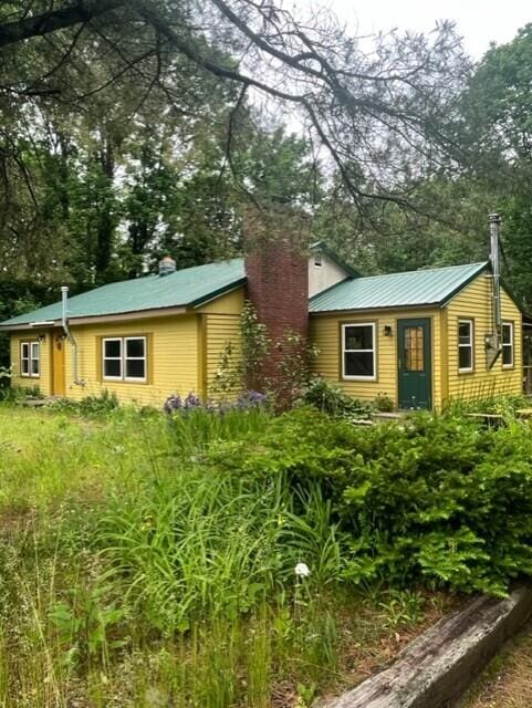 22 Lamb Farm Rd, Brunswick, ME 04011 - view of front of home with a chimney, a metal roof, and view of wooded area