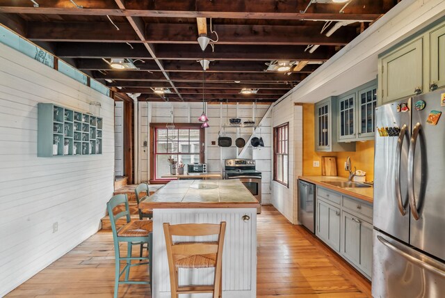 6 Fort Hill Ave, York, ME 03909 - kitchen featuring appliances with stainless steel finishes, wooden walls, a kitchen island, light wood-style flooring, and green cabinetry