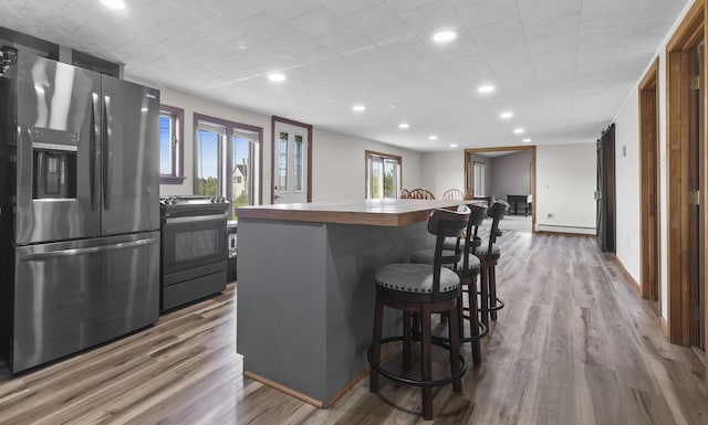 178 Potter Rd, Hudson, ME 04449 - kitchen featuring stainless steel fridge with ice dispenser, range with electric stovetop, wood finished floors, a kitchen breakfast bar, and recessed lighting