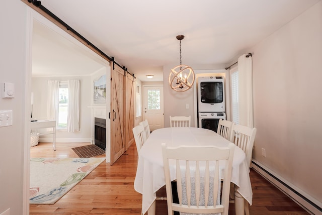 1 Ephraim Tyler Way Unit 1, Kennebunk, ME 04043 - dining area featuring baseboard heating, stacked washer / dryer, a barn door, a chandelier, and light wood finished floors