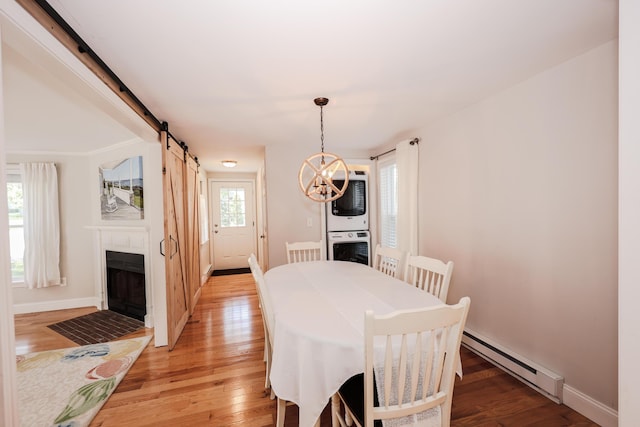 1 Ephraim Tyler Way Unit 1, Kennebunk, ME 04043 - dining room featuring baseboard heating, stacked washing machine and dryer, a chandelier, a barn door, and light wood-type flooring