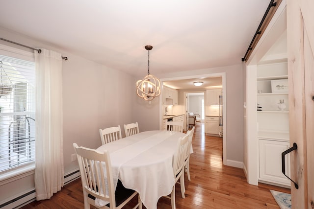 1 Ephraim Tyler Way Unit 1, Kennebunk, ME 04043 - dining area featuring a baseboard heating unit, light wood-style floors, a chandelier, and a barn door