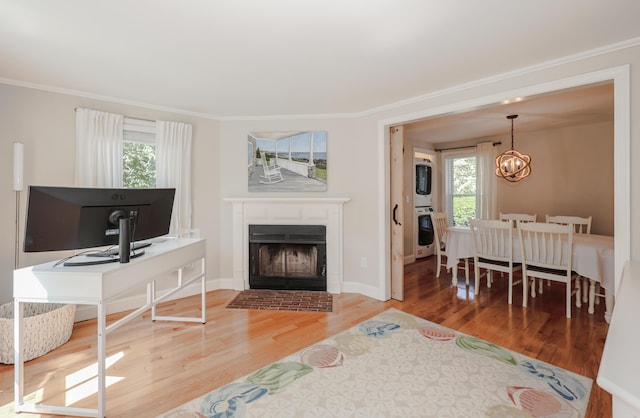 1 Ephraim Tyler Way Unit 1, Kennebunk, ME 04043 - living area with plenty of natural light, ornamental molding, wood finished floors, a fireplace with flush hearth, and a chandelier