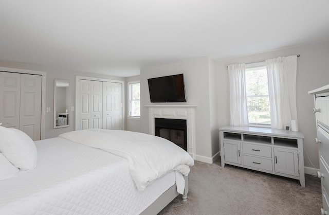 1 Ephraim Tyler Way Unit 1, Kennebunk, ME 04043 - bedroom featuring multiple closets, multiple windows, light carpet, and a fireplace