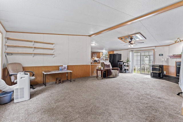 26 Caincrest Rd, York, ME 03909 - carpeted living area with wainscoting, wooden walls, a ceiling fan, and a wood stove