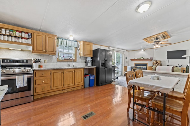26 Caincrest Rd, York, ME 03909 - kitchen with gas range, black refrigerator with ice dispenser, a glass covered fireplace, under cabinet range hood, and light wood-style flooring