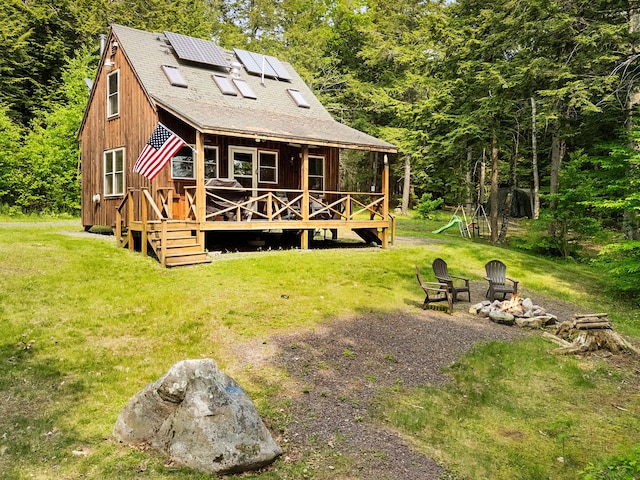 660 Sprague Rd, Waldoboro, ME 04572 - back of property featuring a lawn, a fire pit, roof mounted solar panels, and roof with shingles