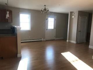 406 Cumberland St, Westbrook, ME 04092 - unfurnished dining area featuring a baseboard radiator, wood finished floors, and a chandelier