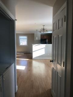 406 Cumberland St, Westbrook, ME 04092 - corridor featuring wood finished floors, a baseboard radiator, and a chandelier