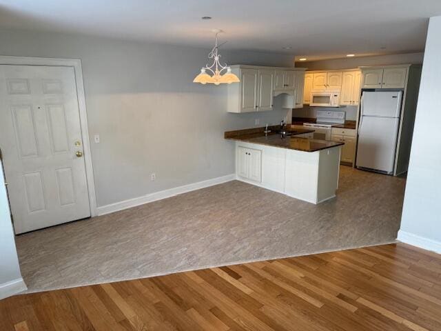 345 Saco St Unit 40, Westbrook, ME 04092 - kitchen featuring white appliances, a peninsula, dark countertops, wood finished floors, and a chandelier