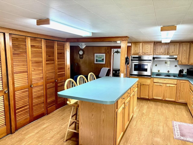 41 York St, Millinocket, ME 04462 - kitchen with stainless steel appliances, a kitchen bar, light wood-style flooring, a kitchen island, and wooden walls
