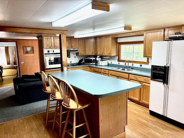 41 York St, Millinocket, ME 04462 - kitchen featuring white appliances, light wood-style floors, a breakfast bar, and brown cabinets