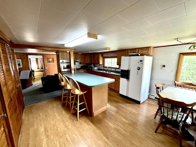 41 York St, Millinocket, ME 04462 - kitchen featuring white refrigerator with ice dispenser, stainless steel oven, light wood finished floors, a breakfast bar area, and a center island