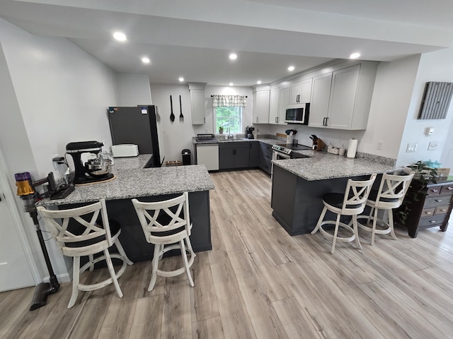 1083 N Rd, Newburgh, ME 04444 - kitchen with stainless steel appliances, a peninsula, light wood-type flooring, light stone countertops, and recessed lighting