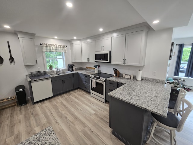 1083 N Rd, Newburgh, ME 04444 - kitchen with white appliances, a peninsula, light stone counters, recessed lighting, and healthy amount of natural light
