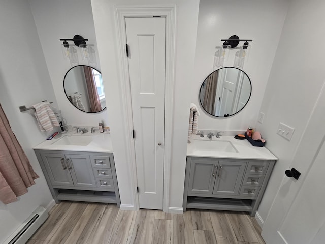 1083 N Rd, Newburgh, ME 04444 - full bath featuring a baseboard radiator, wood finished floors, and two vanities