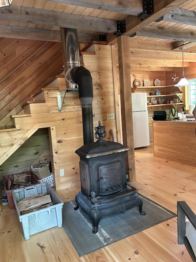 704 Sawyers Mills Rd, Starks, ME 04911 - detailed view of freestanding refrigerator, a wood stove, wood walls, a wooden ceiling with exposed beams, and wood finished floors