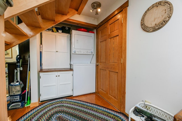 365 Waterville Rd, Skowhegan, ME 04976 - laundry room featuring stacked washing machine and dryer, wood finished floors, and cabinet space