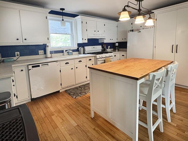19 Union St, Hallowell, ME 04347 - kitchen with white appliances, under cabinet range hood, light wood-style floors, white cabinets, and a breakfast bar area