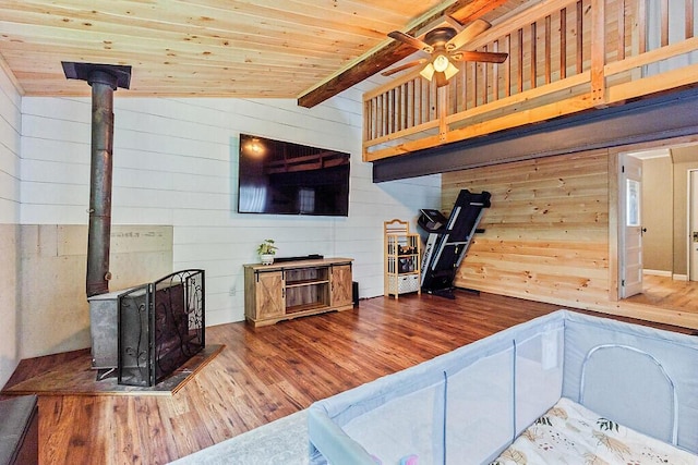 171 Bassett Rd, Winslow, ME 04901 - living room with a wood stove, wood finished floors, wood walls, a ceiling fan, and wood ceiling