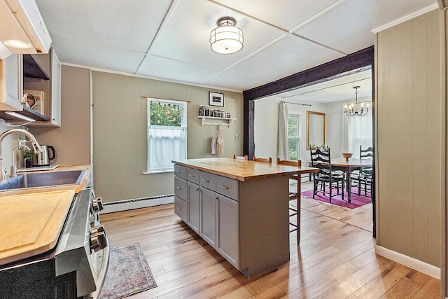 171 Bassett Rd, Winslow, ME 04901 - kitchen featuring butcher block countertops, a baseboard radiator, gray cabinetry, a breakfast bar area, and healthy amount of natural light