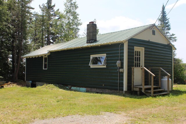 189 E Shore Rd, Benedicta Twp, ME 04733 - view of property exterior featuring a chimney, a yard, and a metal roof